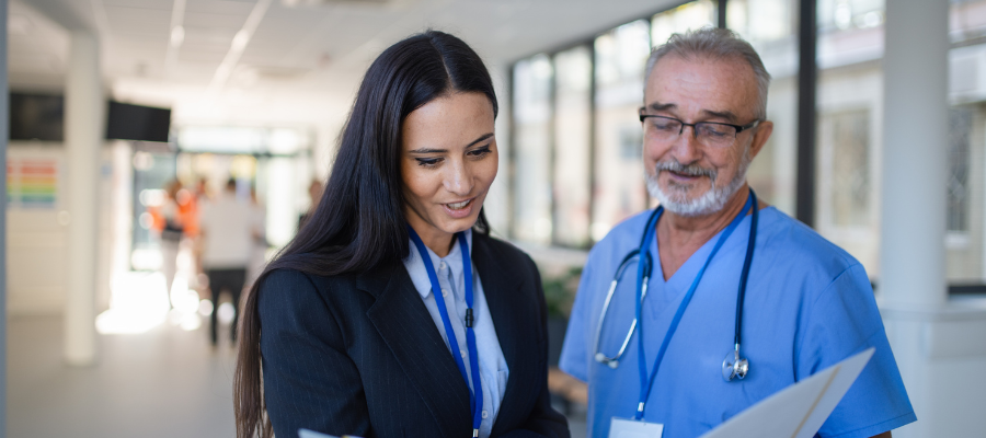 Medical professional in scrubs reviewn document with business profesional in suit